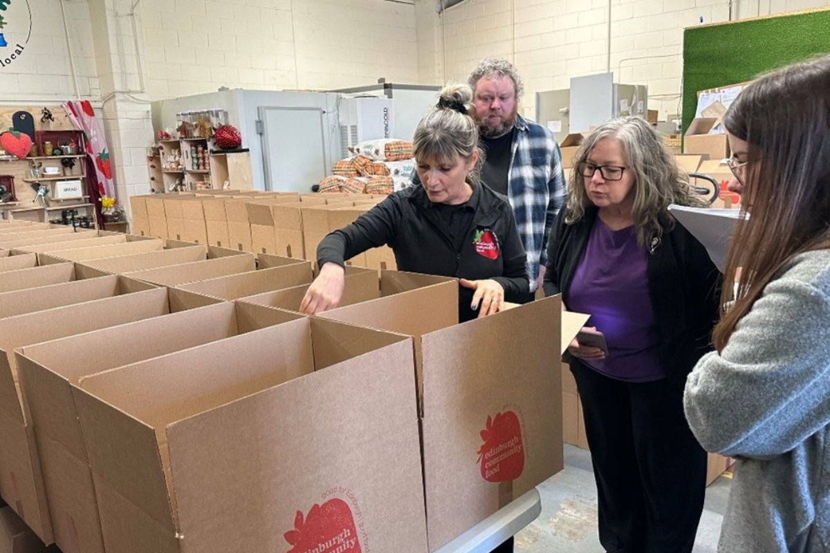 A group of people exploring cardboard boxes for community food delivery.
