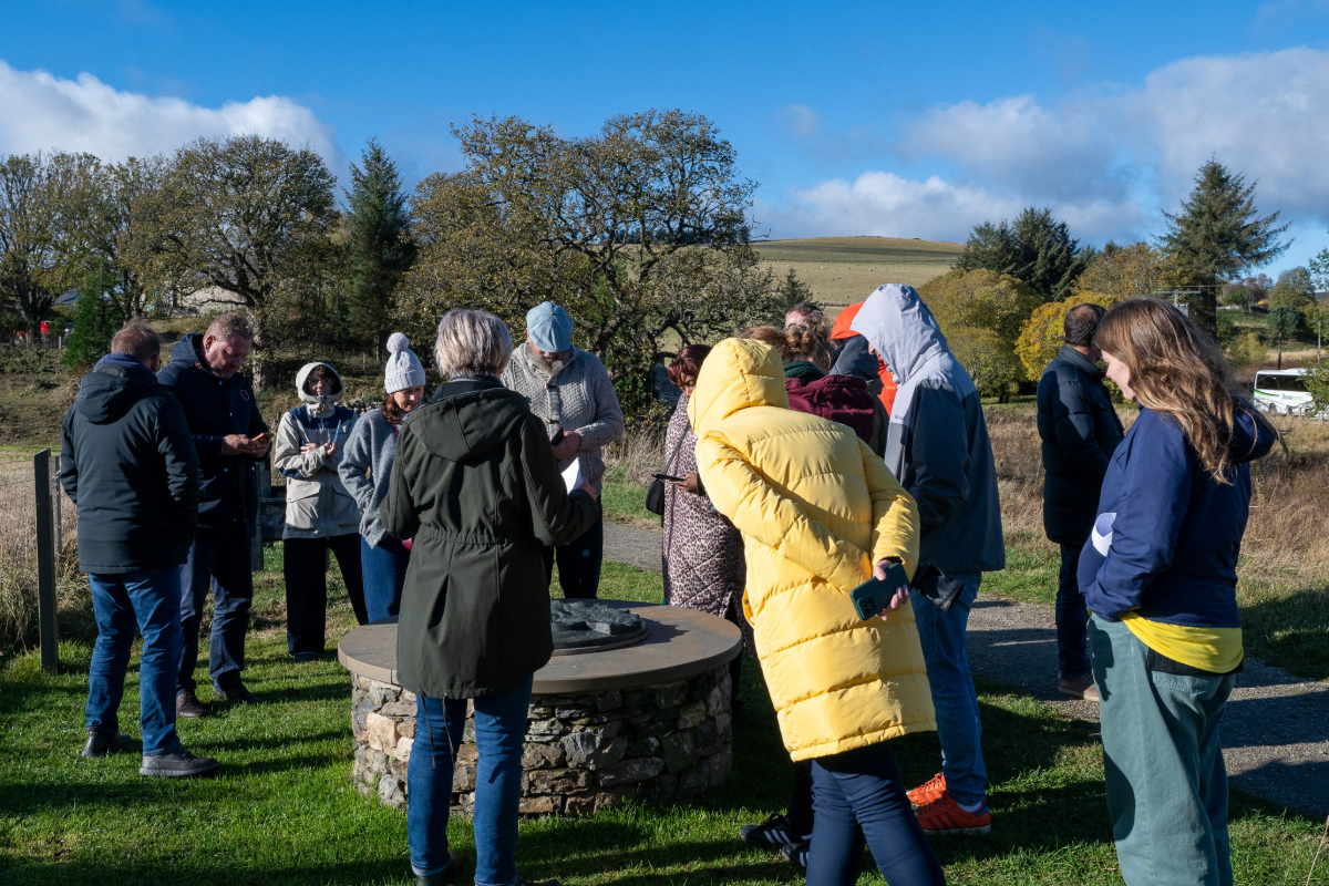 A group of people outside standing round a circular stone plaque