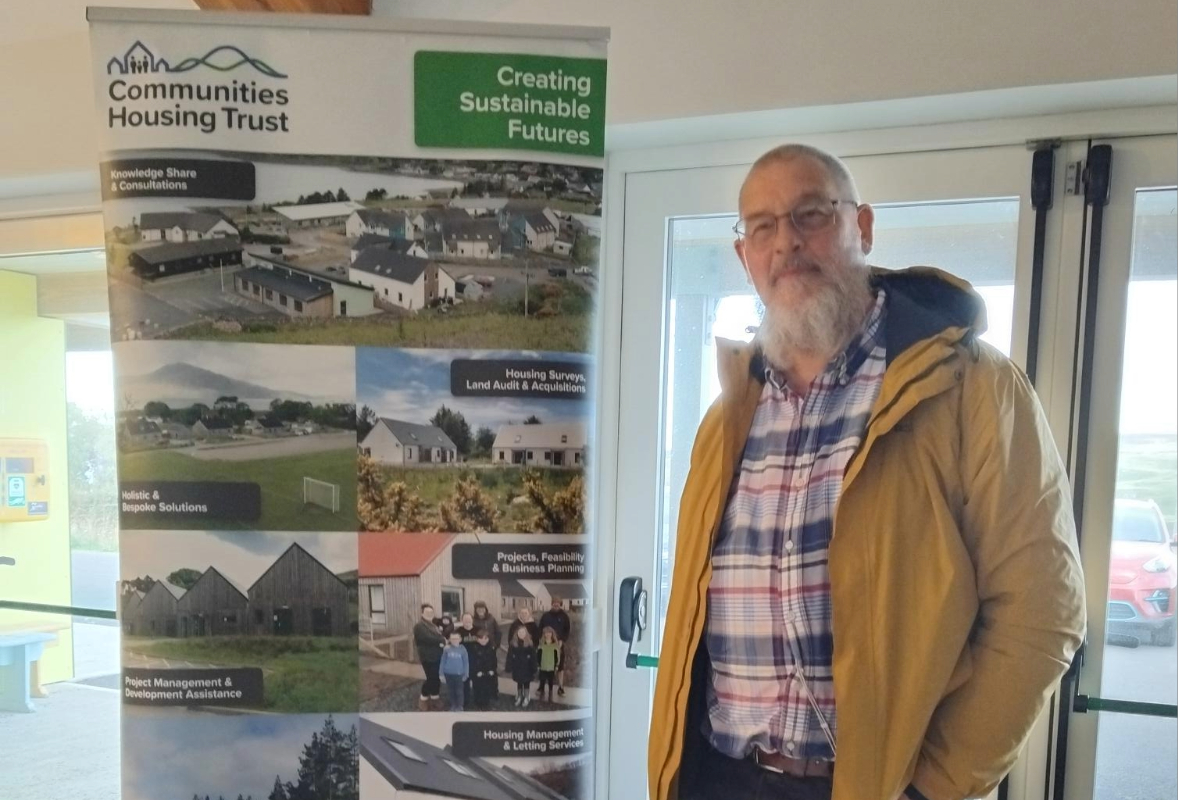 A person standing next to Communities Housing Trust pop up banner