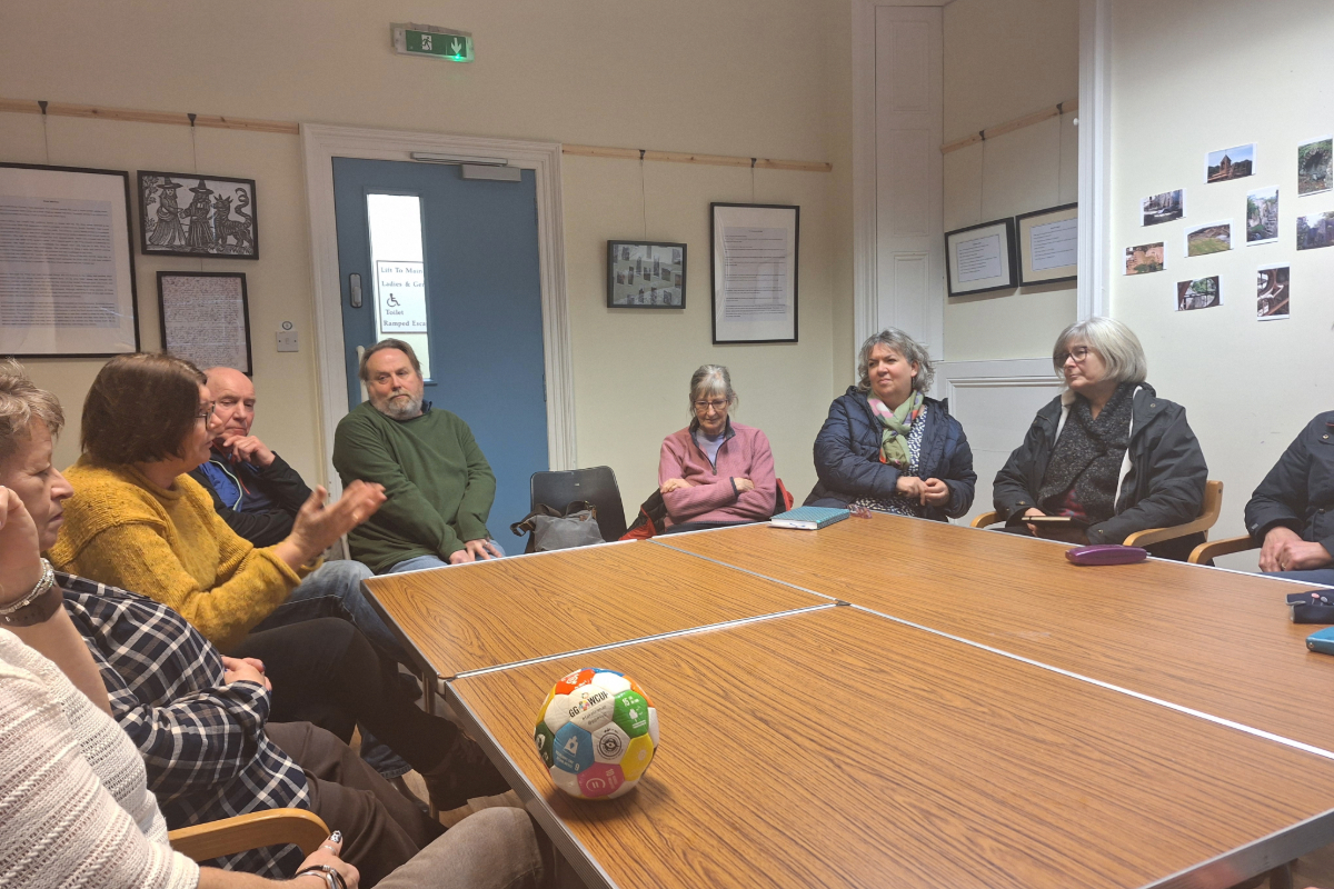 A group of 9 people sitting round a table in discussion
