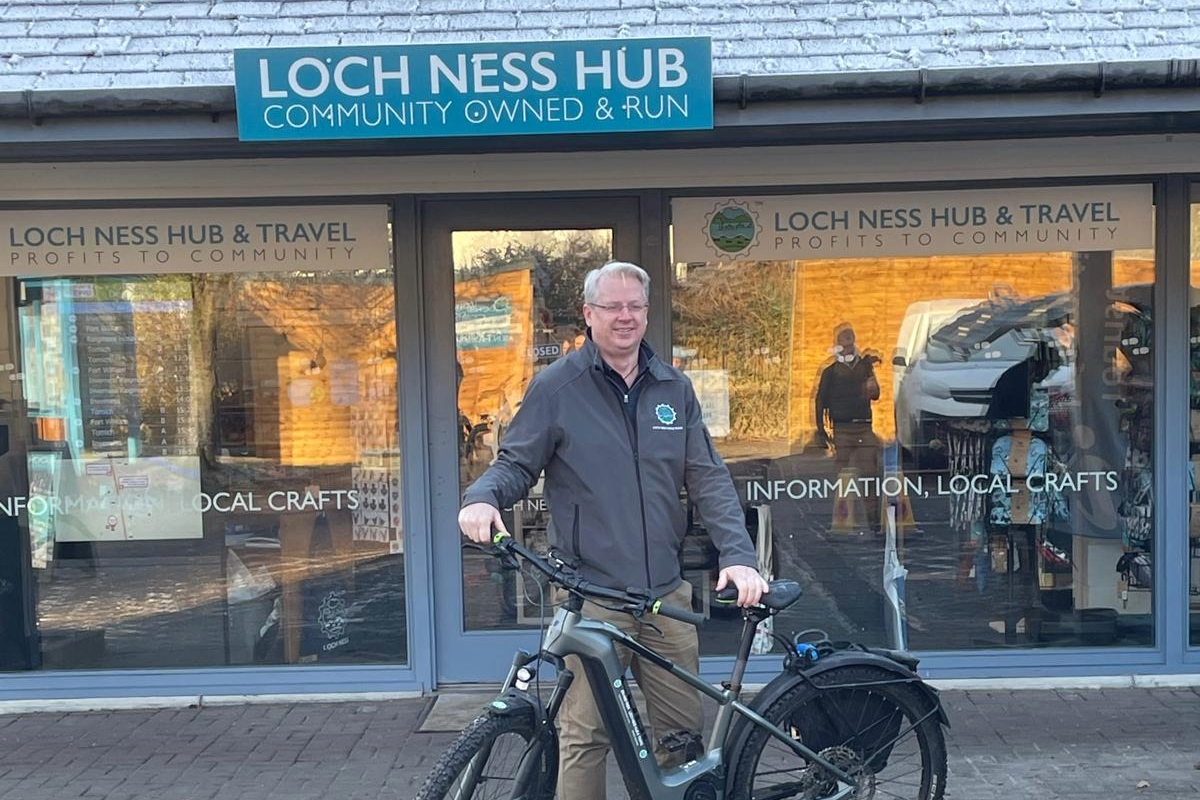 Loch Ness Community owned & run hub with a person holding a bike at the front of the hub