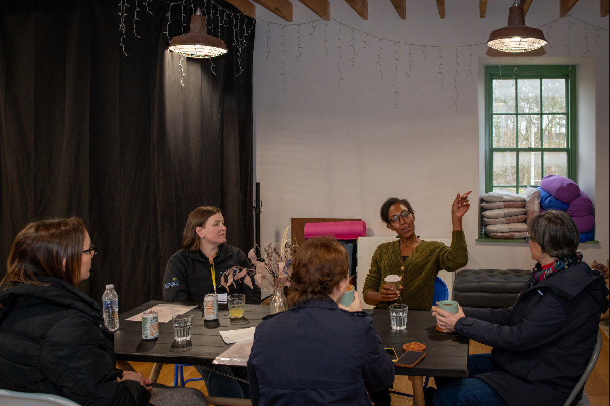 A group of 5 people sitting round a table chatting