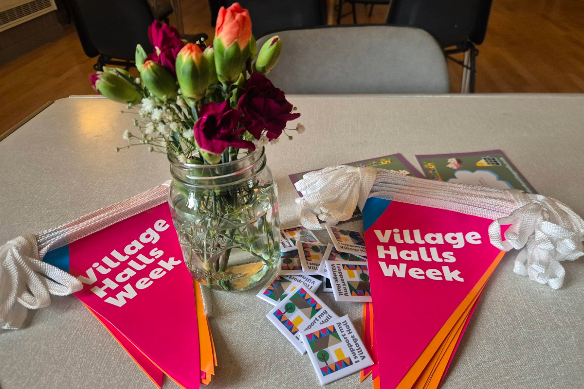 Image of a jar with flowers surrounded by village halls bunting and flyers