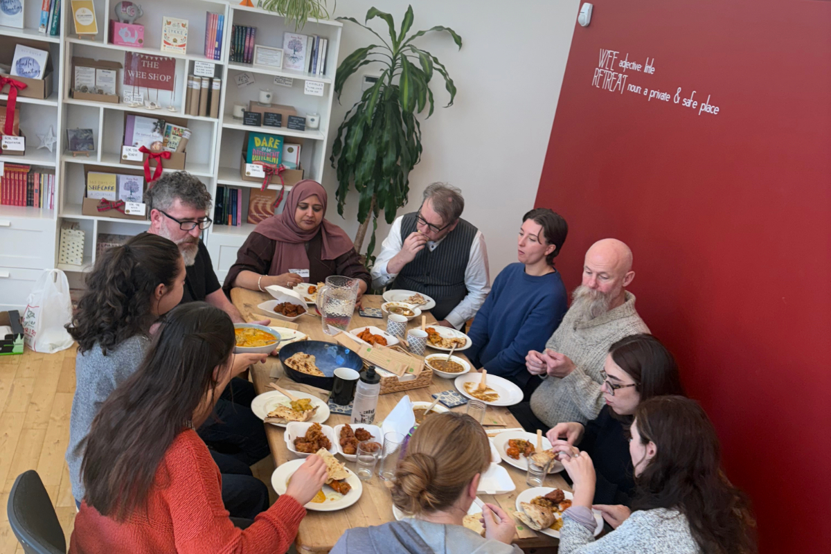 A group of 8 people sharing food around a table
